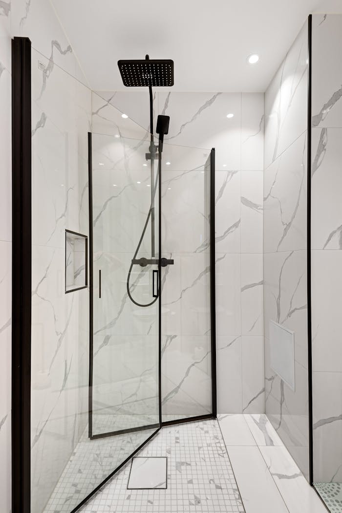 gallery-06 Elegant modern shower featuring sleek marble tiles and a glass door for a minimalist aesthetic.